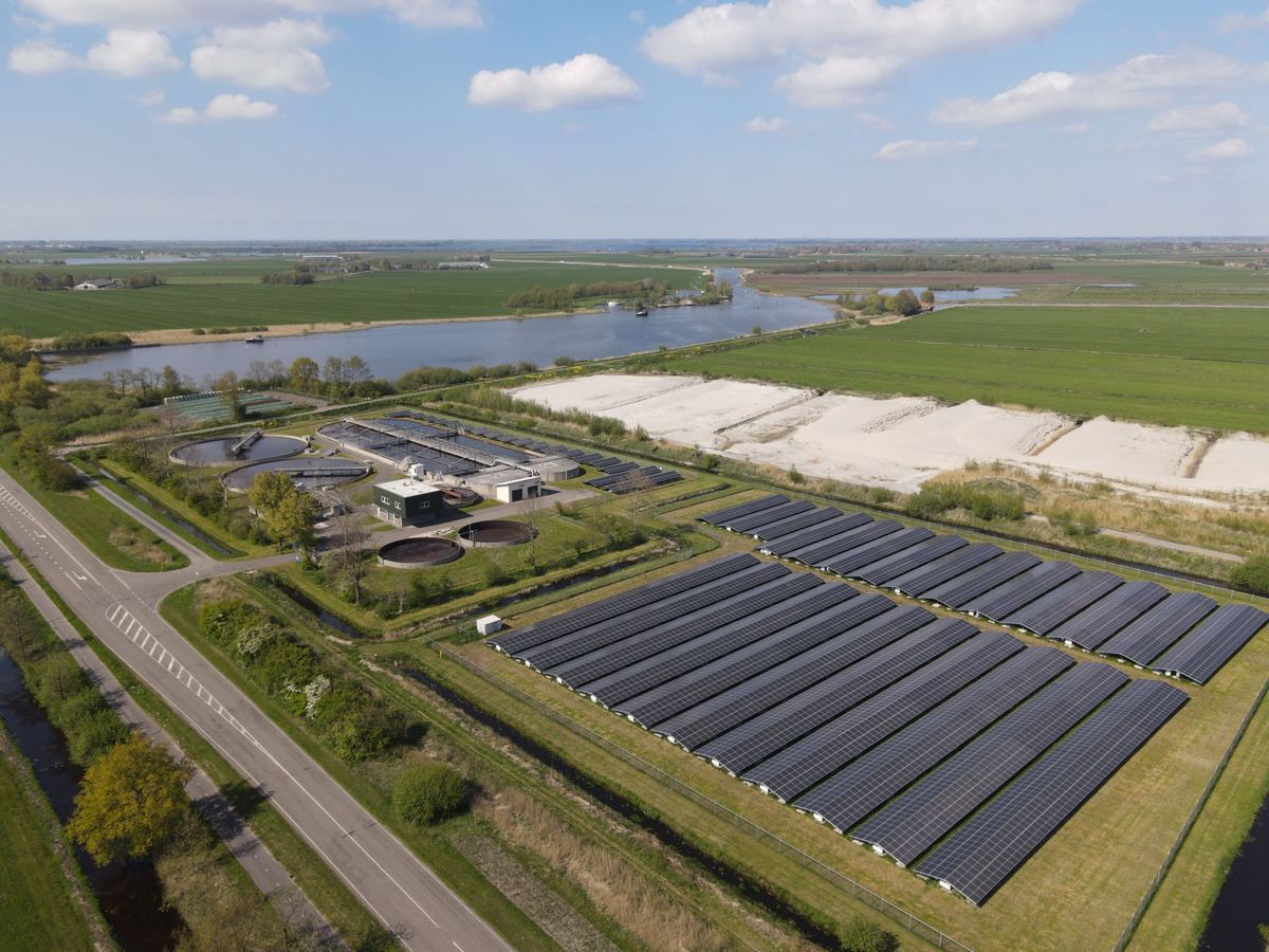 Saulės elektrinių parkas šalia upės ir laukų iš paukščio skrydžio